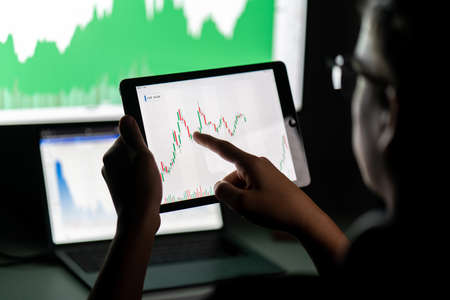 Crypto trader investor analyst looking at computer screen analyzing financial graph data on pc monitor, thinking of online stock exchange market .の写真素材