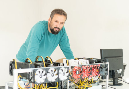 Young programmer adjusting cryptocurrency mining rig to optimal operational settings. High quality...