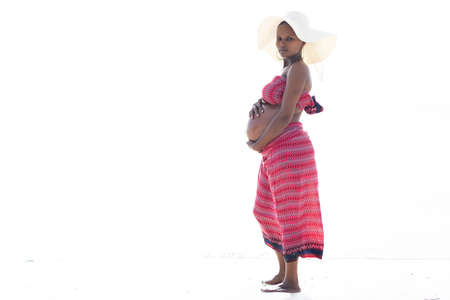Pregnant African woman with hat at the beach. High quality photoの写真素材