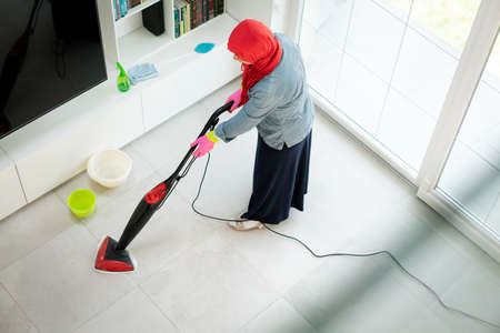 Happy Muslim Woman Cleaning Modern House Living Room. High quality photoの写真素材
