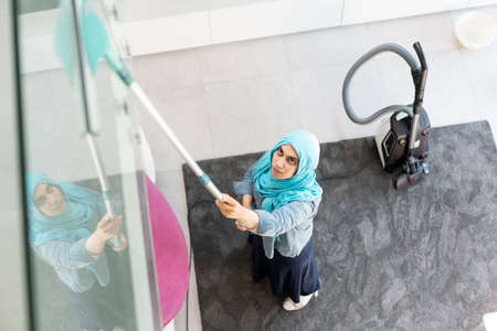 Happy Muslim Woman Cleaning Modern House Living Room. High quality photoの写真素材
