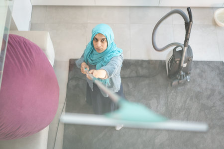 Happy Muslim Woman Cleaning Modern House Living Room. High quality photo