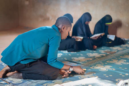African teenage boys and girls sitting and reading book in poor school, high quality photoの写真素材