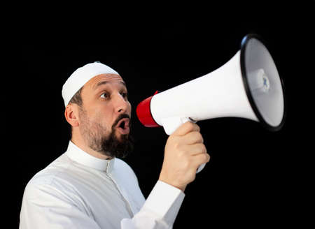 Muslim pilgrim in white traditional clothes, saying message on megaphone. High quality photoの写真素材