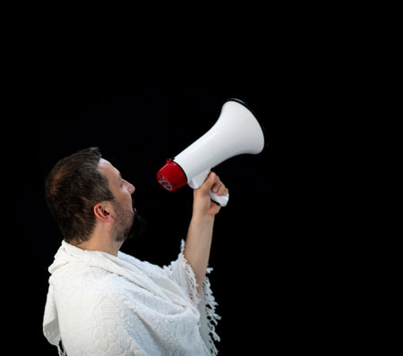 Muslim pilgrim in white traditional clothes, saying message on megaphone. High quality photoの写真素材