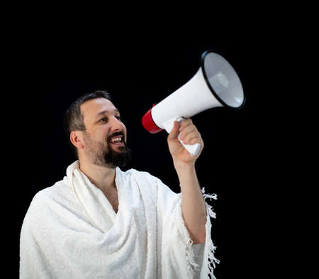 Muslim pilgrim in white traditional clothes, saying message on megaphone. High quality photoの写真素材