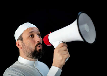 Muslim pilgrim in white traditional clothes, saying message on megaphone. High quality photoの写真素材
