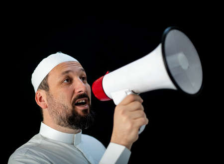 Muslim pilgrim in white traditional clothes, saying message on megaphone. High quality photoの写真素材