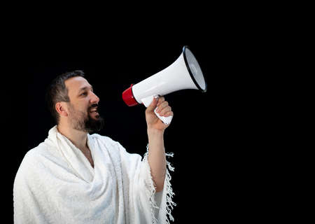 Muslim pilgrim in white traditional clothes, saying message on megaphone. High quality photoの写真素材