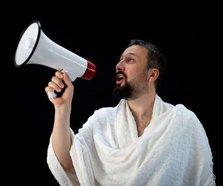 Muslim pilgrim in white traditional clothes, saying message on megaphone. High quality photoの写真素材