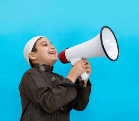 Muslim child in white traditional clothes, saying message on megaphone. High quality photoの写真素材