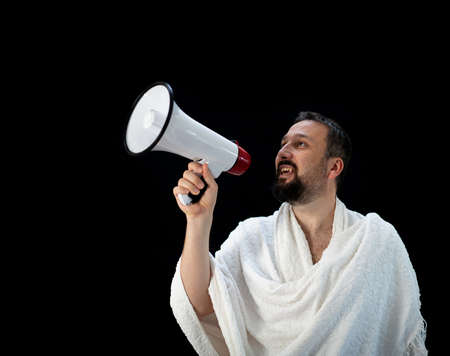 Muslim pilgrim in white traditional clothes, saying message on megaphone. High quality photoの写真素材