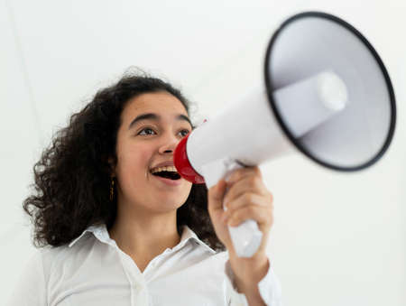 Beautiful business woman with curly hair holding a megaphone. High quality photoの写真素材