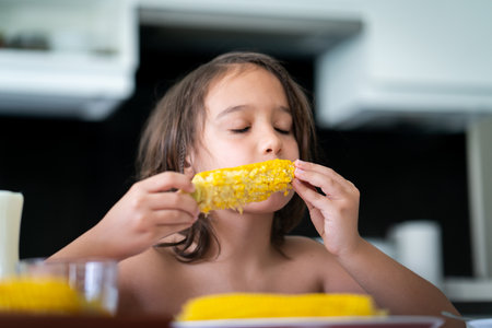 Summer snack, little boy sitting and eating corn High quality photoの写真素材