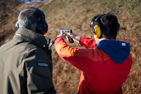 Trainer helping young person to aim with handgun at combat training. High quality photoの写真素材
