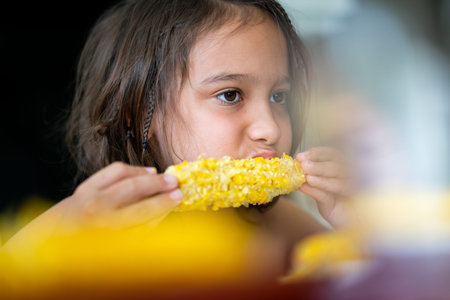 Summer snack, little boy sitting and eating corn High quality photo