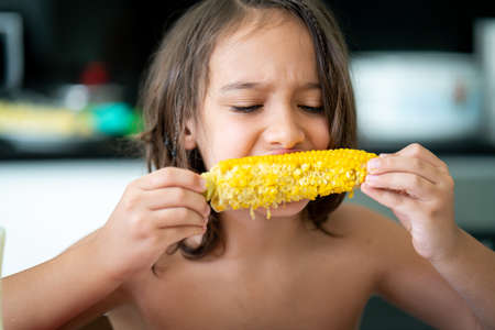 Summer snack, little boy sitting and eating corn High quality photoの写真素材