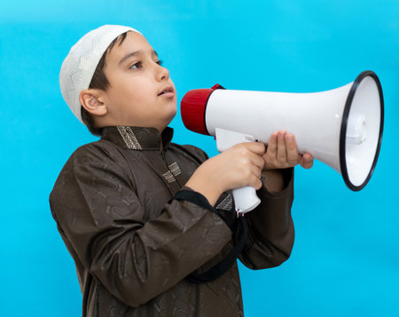 Little boy using megaphone shouting on blue background. High quality photoの写真素材