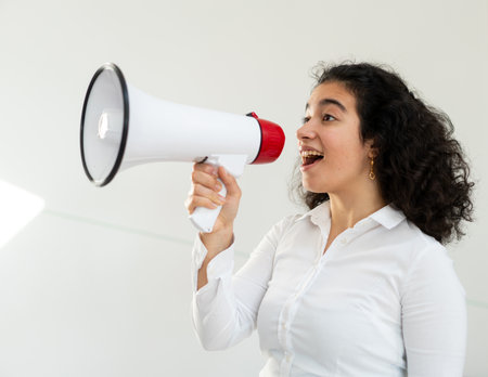 Beautiful business woman with curly hair holding a megaphone. High quality photoの写真素材