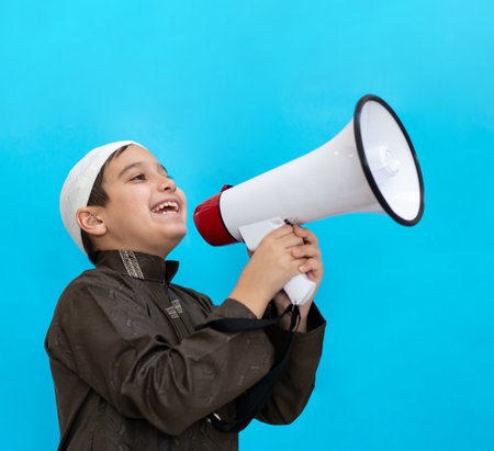 Little boy using megaphone shouting on blue background. High quality photoの写真素材