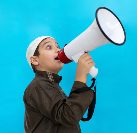 Little boy using megaphone shouting on blue background. High quality photoの写真素材