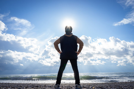 Boy standing on winter beach making shadow silhouetteの写真素材