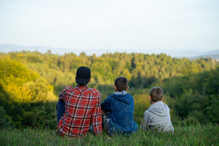 Little boys on a green meadow looking into the distance at the forest. High quality photoの写真素材
