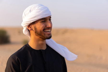 Close up portrait of happy man wearing traditional arab clothing, standing in hot arabian desert. High quality photoの写真素材
