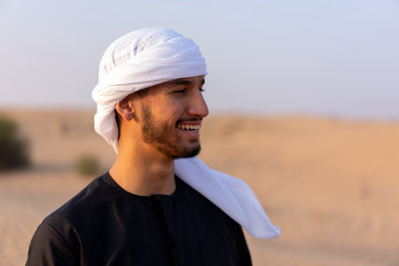 Close up portrait of happy man wearing traditional arab clothing, standing in hot arabian desert. High quality photoの写真素材
