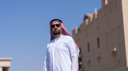 Man wearing traditional arab clothing walking outside in the city. Beautiful sunny weather. High...