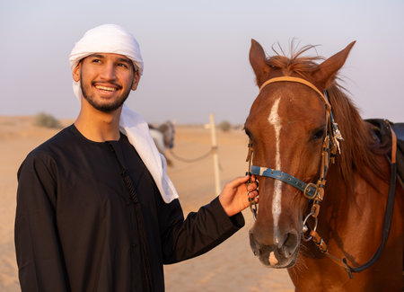 Arab man wearing traditional clothing petting a horse in the middle of the desert. High quality photoの写真素材
