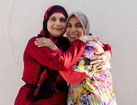 Two women wearing hijab hugginh and looking at camera. High quality photoの写真素材