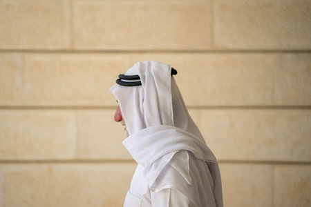An adult Muslim man in white traditional clothes looks at the camera and expresses emotions. Elderly male on a background. High quality photoの写真素材