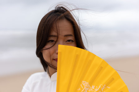 Portrait of thai woman at the beach holding hand fan. High quality photoの写真素材