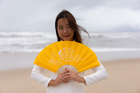 Portrait of thai woman at the beach holding hand fan. High quality photoの写真素材