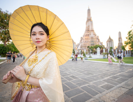 Beautiful Asian woman posing for photograph wearing traditional clothing at Wat Arun Buddhist temple. High quality photoの写真素材
