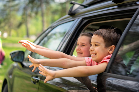Two happy siblings looking out of car window enjoying summer breeze. High quality photoの写真素材