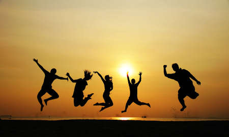 5 people jumping at the beach when sunsetの写真素材