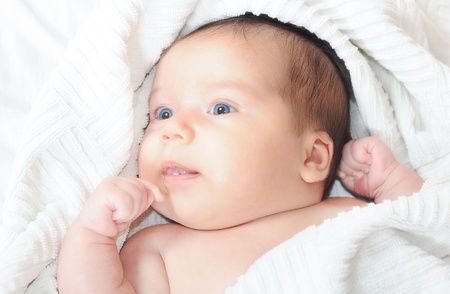Cute blue-eyed newborn baby in a white towel after having a bath.の写真素材