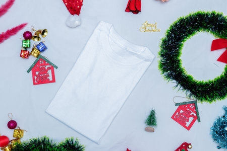 Blank folded shirt mockup image with christmas decorations. A blank folded shirt encircled by christmas ornaments, colorful gift decorations. Blank space to fill. Christmas folded shirt mockup imageの写真素材