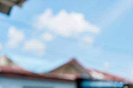 Defocused abstract background of a blue sky with a small building in the frame. Blurred out village backgroundの写真素材