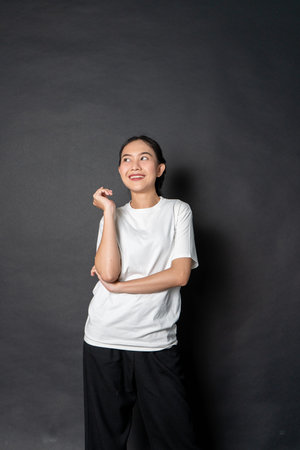 An asian woman with a white blank shirt giving happy while facing sideways with the black backgroundの写真素材