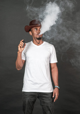 An african man with blank white v-neck shirt doing a pose while smoking , on the black background
