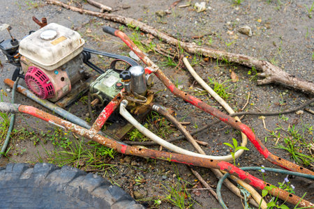 Broken lawn mower laying out on the top of a sand road close to a big black tireの写真素材