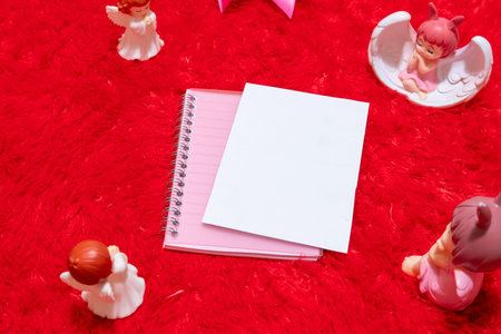 White blank notebook paper on the top of a notebook surrounded by valentine themed decorations, and...