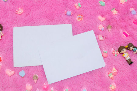 Two rectangle greeting card above a pink fluffy carpet surrounded by tiny decorations with valentine...