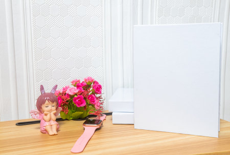 A standing white colored hardcover books on the top of a brown table with wooden texture and some decorations arranged around it, hardcover mockup template imageの写真素材
