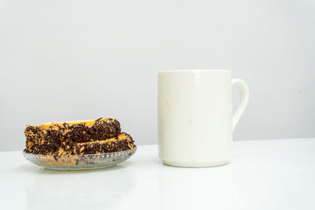 A white blank coffee mug standing out on the top of a white book with a snack placed near it, coffee...