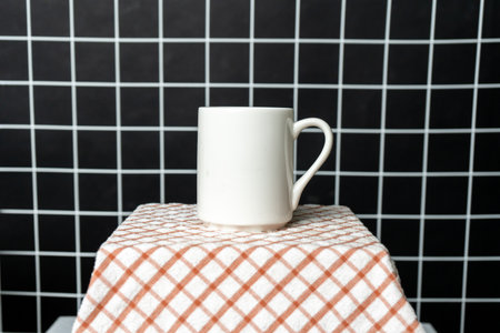 A white blank coffee mug on the top of a hand cloth with the white wire grid as the background, coffee mug mockup imageの写真素材