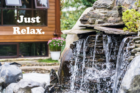 Motivational quote - Just relax. With a small fountain on the right side and an out of focus wooden buildingの写真素材